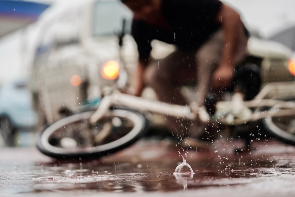 Cyclist fallen on wet pavement near a truck in Baltimore